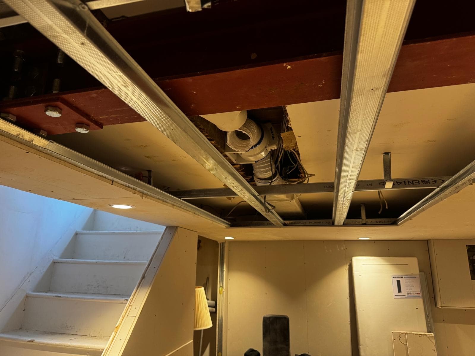 New steel beam bolted in above the basement with the ceiling framing and extract ducting exposed around it