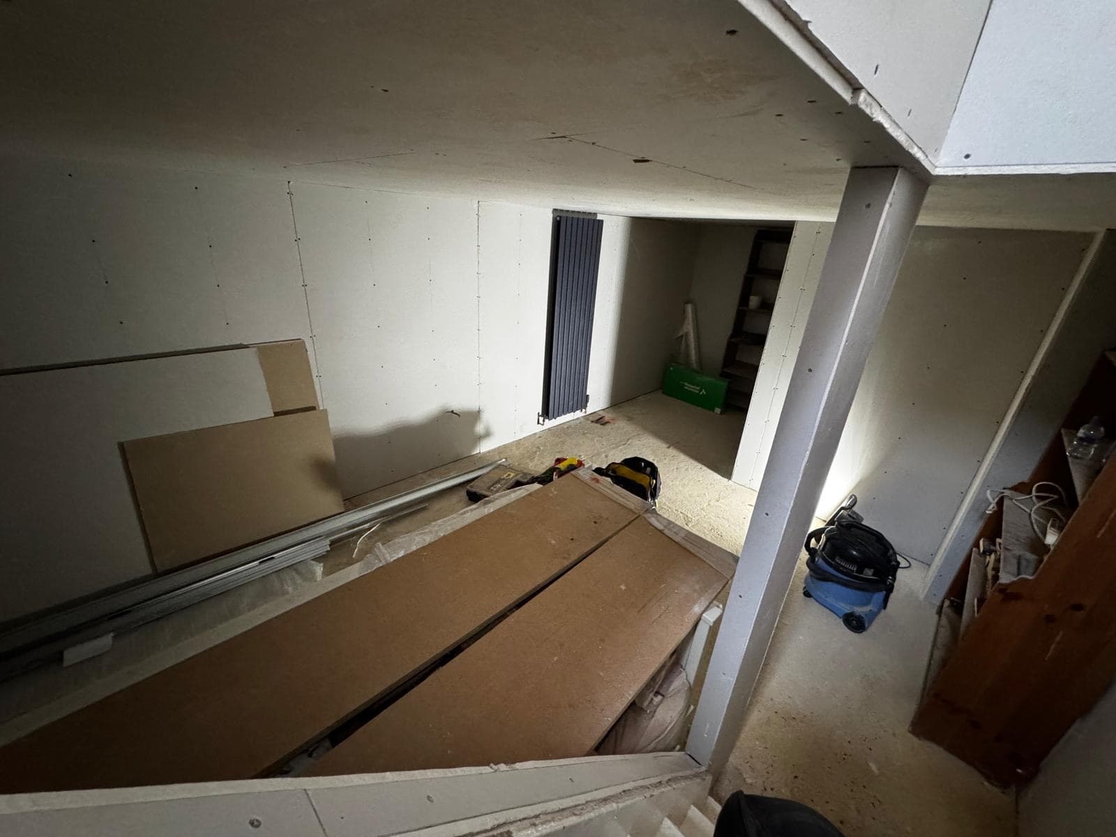 Basement boarded out with the vertical radiator hung and flooring stacked ready to lay