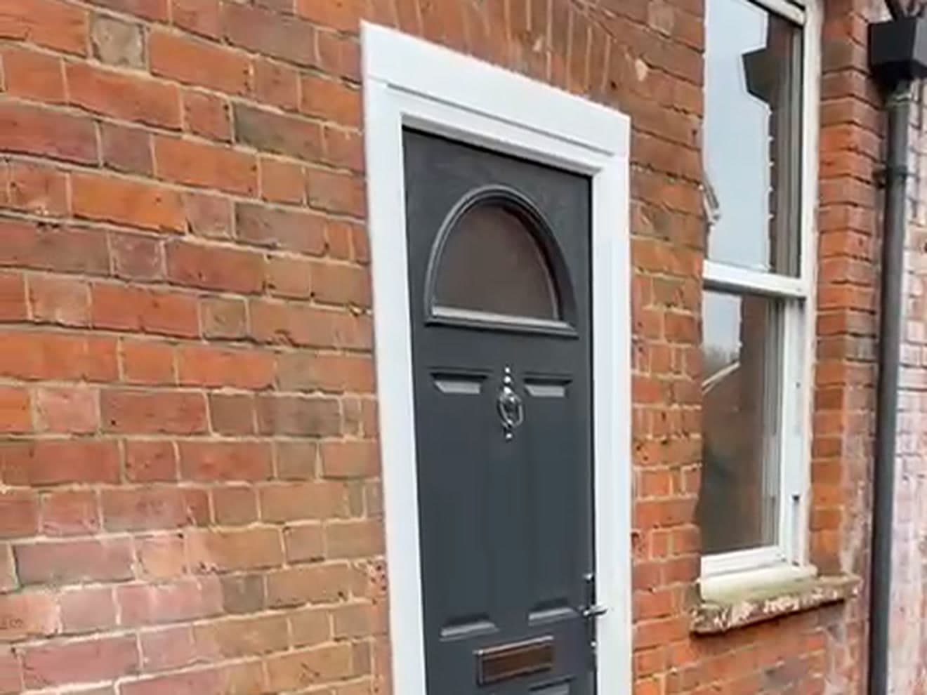 The front of a red brick house with a new grey composite front door, arched fanlight and chrome knocker beside a white sash window